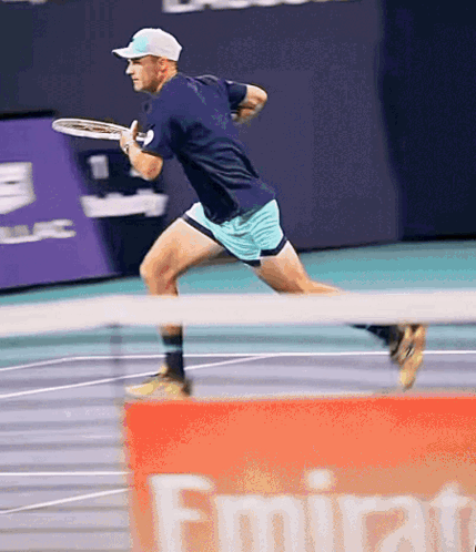 Man Playing Tennis in Front of Emirates Banner