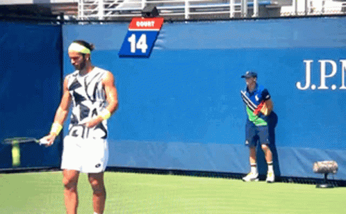 Man Playing Tennis in Front of Wall With Number 14