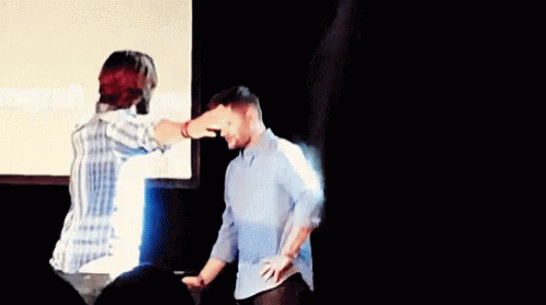 Man Pointing At Another Man's Head In Front Of Screen GIF
