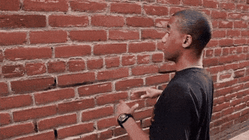 Man Pointing at Brick Wall