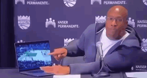 Man Pointing at Laptop in Front of Microphone