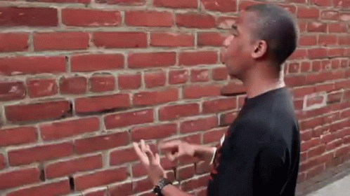 Man Pointing at Red Brick Wall