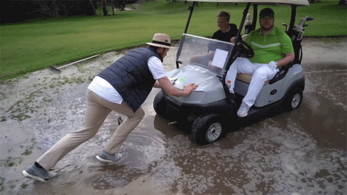 Man Pushing Golf Cart Through Muddy Field