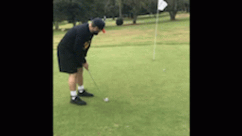 Man Putting Golf Ball on Green