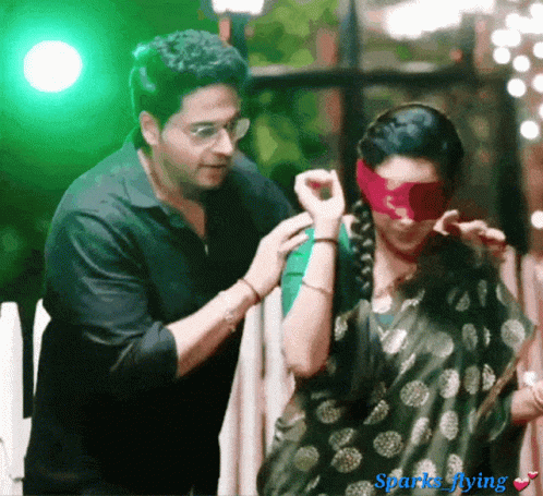Man Putting Red Blindfold on Woman With Sparks Flying