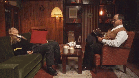 Man Reading Book Beside Woman on Couch
