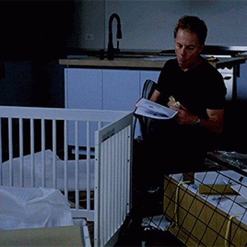 Man Reading Book in Front of Baby Crib