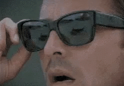 Man Removing Sunglasses and Looking