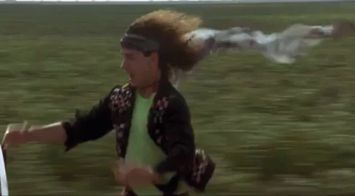 Man Riding Bicycle With Flying Scarf in Field