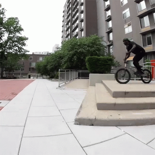 Man Riding Bike Down Stairs Past Building Saying A