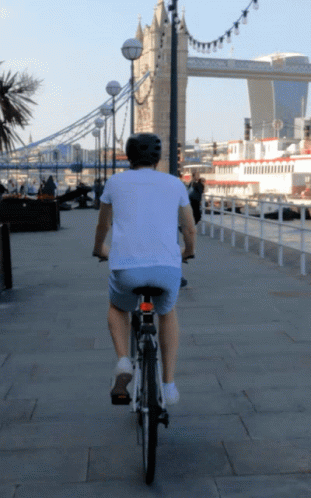 Man Riding Bike in Front of Bridge