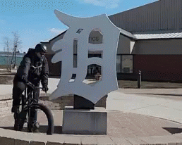 Man Riding Bike in Front of Detroit Tigers Sign