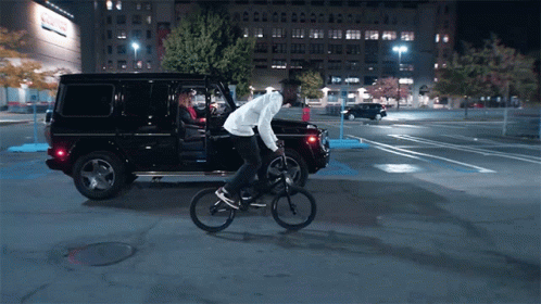 Man Riding Bike Next to Black SUV