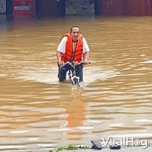 Man Riding Bike Through Flooded Street GIF