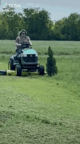 Man Riding Lawn Mower Through Field