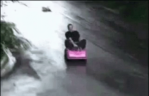 Man Riding Pink Sled Down Flooded Street