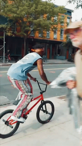Man Riding Red Bike Down Street
