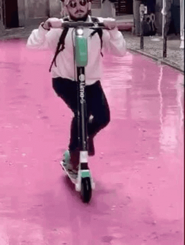 Man Riding Scooter Down Pink Street