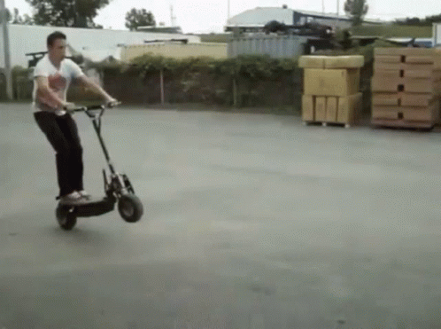 Man Riding Scooter in Parking Lot