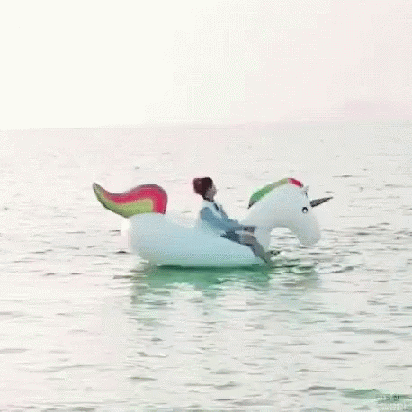 Man Riding Unicorn Float In Ocean GIF