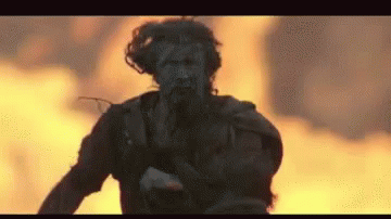 Man Running in Front of Fire With Gun