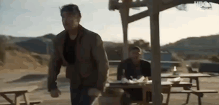 Man Running Towards Picnic Table While Another Man Sits GIF