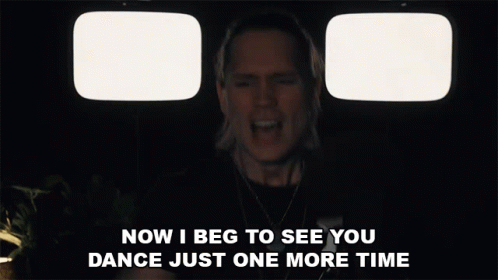 Man Singing in Front of Two Televisions Saying Now I Beg to See You Dance Just One More Time