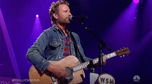 Man Singing Into Microphone Holding Acoustic Guitar With WSM