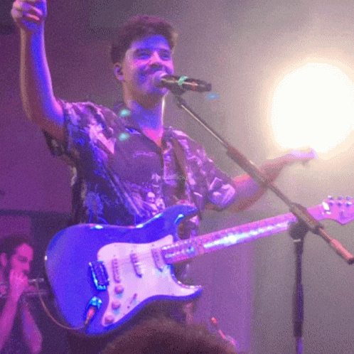 Man Singing Into Microphone Holding Guitar