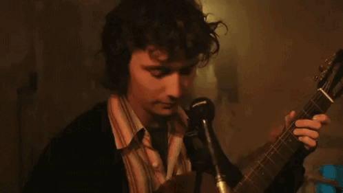 Man Singing Into Microphone Holding Guitar