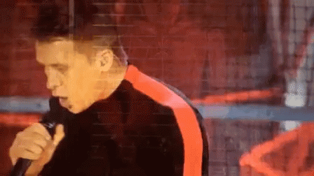 Man Singing Into Microphone in Black and Red Jacket