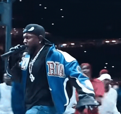 Man Singing Into Microphone in Blue Ria Jacket