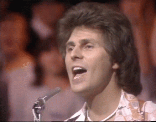 Man Singing Into Microphone in Front of Crowd