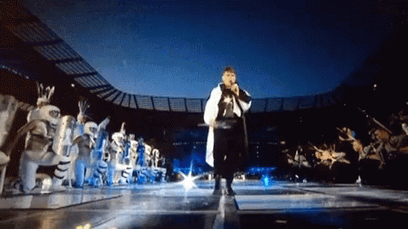 Man Singing Into Microphone In Front Of Crowd GIF