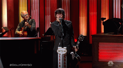 Man Singing Into Microphone Next to WSM Gran Sign