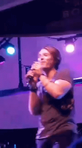 Man Singing Into Microphone on Stage