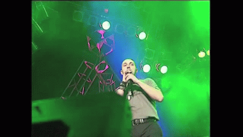 Man Singing Into Microphone on Stage With Green Lights