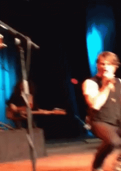 Man Singing Into Microphone Playing Guitar