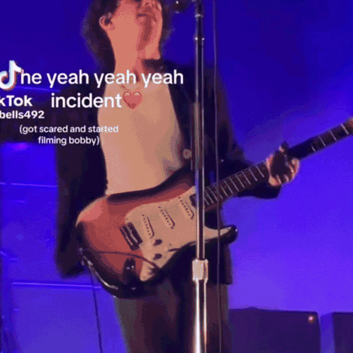 Man Singing Into Microphone Playing Guitar Purple Background GIF