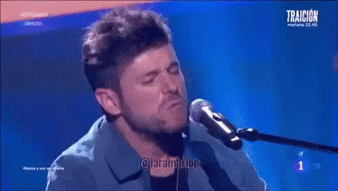 Man Singing Into Microphone Playing Piano Blue Background Traicion