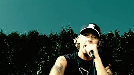 Man Singing Into Microphone Wearing Hat With Letter E GIF