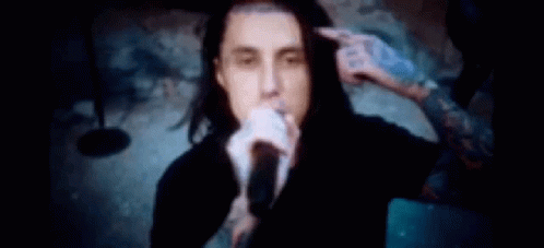 Man Singing Into Microphone While Another Holds His Hair