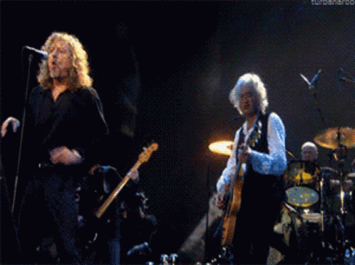 Man Singing Into Microphone While Man Plays Guitar