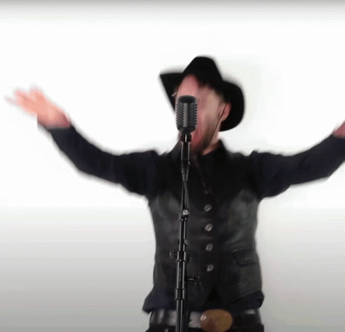 Man Singing Into Microphone With Arms Outstretched