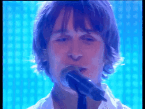 Man Singing Into Microphone With Blue Background
