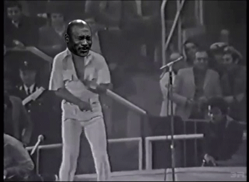 Man Singing Into Microphone With Crowd Behind