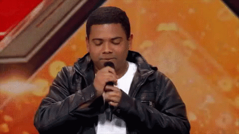 Man Singing Into Microphone With Eyes Closed