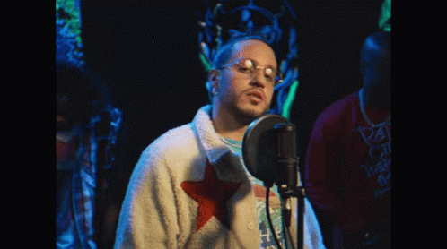 Man Singing Into Microphone With Glasses And White Jacket With Red Star GIF