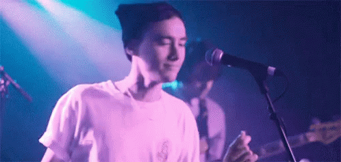 Man Singing Into Microphone With Guitar GIF
