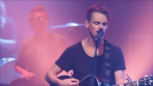 Man Singing Into Microphone With Guitar